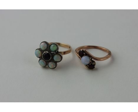 A 9ct gold, garnet and opal ring, having central round cut garnet in rub over white metal setting surrounded six round caboch