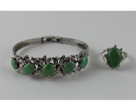 A 14ct. white gold and jade ring, the raised centre four claw set oval cabochon apple green jade surrounded eight diamond chi