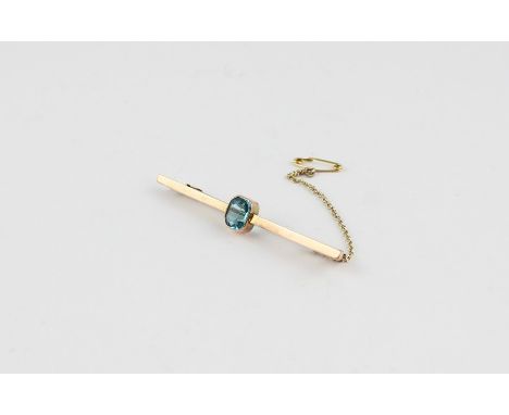 A yellow metal and blue stone bar brooch,&nbsp;having emerald cut blue stone to centre, (yellow metal assessed as 9 carat ros