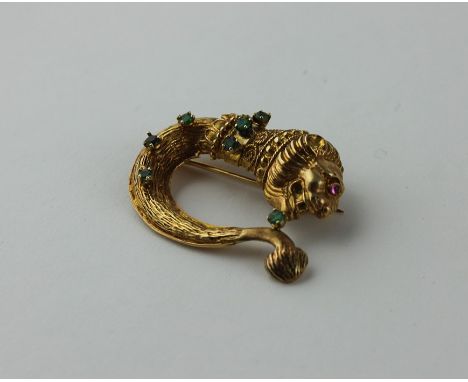 An 18ct. yellow gold and emerald brooch,&nbsp; fashioned as a stylised lion, the head with mane and cabochon ruby eye, the ne