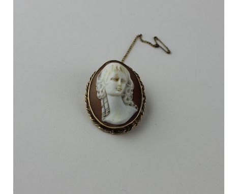 A 9ct. gold mounted oval shell cameo brooch, carved in high relief with a bust portrait of a lady, within gold mount undulati