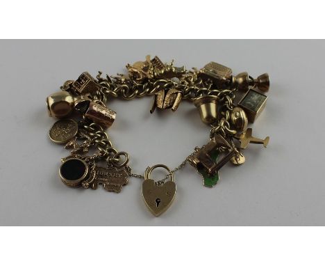 A 9ct. yellow gold curb link charm bracelet suspending an extensive collection of gold charms,&nbsp;bracelet links impressed 