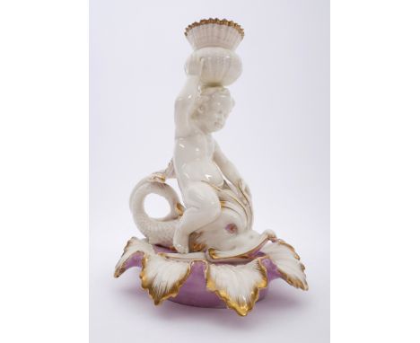 1863-91 Belleek lustreware figural candlestick. A first-period porcelain candlestick in the form of a cherub astride a dolphi