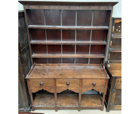 An 18th century Welsh oak dresser with a moulded cornice above three shelves and a planked back, the base with a rectangular 