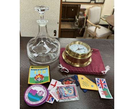 A decanter together with a quartz and brass clock, badges etc