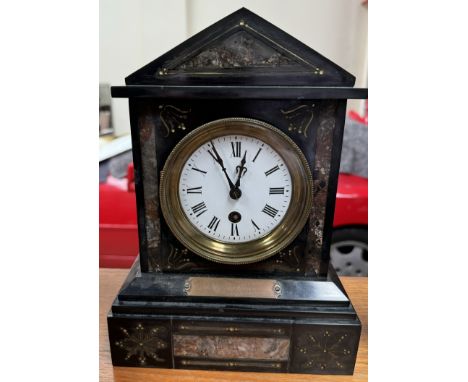 A black slate mantle clock, of architectural form with a circular dial and Roman numerals