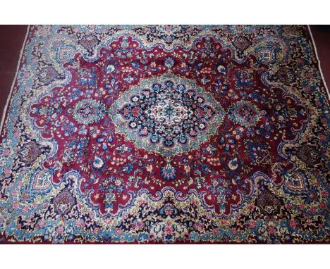 A North East Persian Meshad carpet, central double pendant medallion with repeating petal motifs on a pomegranate field, comp