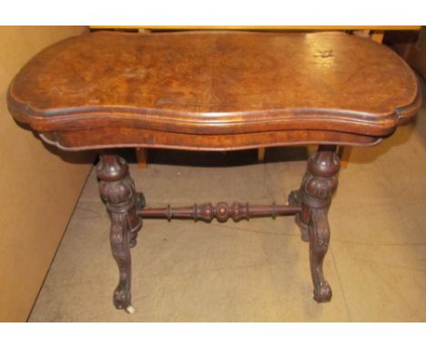 A Victorian walnut card table with a hinged shaped top with a baize interior on carved and turned uprights and carved legs
