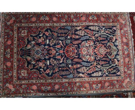 A Kashan prayer rug, the indigo mihrab hung with lantern, a vase below, amongst trees, flowers, and birds within a main madde