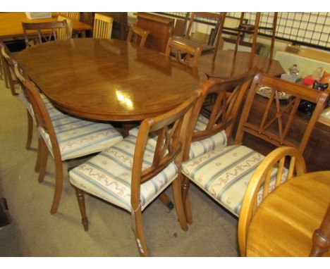 A Regency yew wood twin pillar dining table with a cross-banded top including an extra leaf on two ring turned columns with s