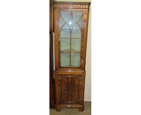 A Georgian style yew wood standing corner cupboard, the pendant frieze above an astragal glazed door and panelled door below,