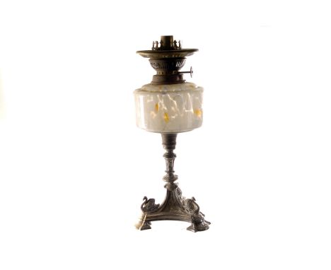 An early 20th century paraffin lamp, with globe shade and smokestack, surmounting a mottled glass reservoir, supported on a s