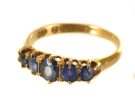 An 18ct gold and gem set five stone ring, having blue sapphire style graduating stones in hallmarked mount