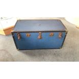 Vintage blue steamer trunk with metal hardware and riveted edges. Features a plaid-lined interior