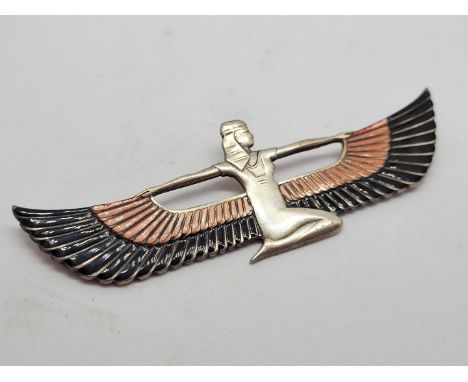 An Art Deco silver and enamel brooch, modelled as an Egyptian goddess with winged cloak, depicted kneeling with pin back, in 