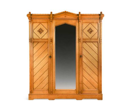 In the manner of Charles Bevan, a late Victorian ash triple wardrobe, the arched central mirror flanked by panel doors with p