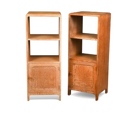 A pair of Heal's limed oak bedsides, circa 1930, each with two open book shelves above a single door cupboard with panelled b