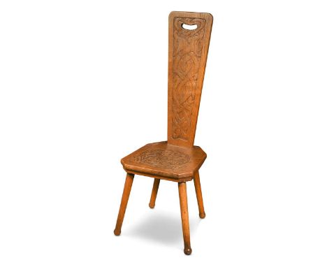 An Arts & Crafts carved oak spinning chair, decorated with Celtic knots and serpent heads107cm high