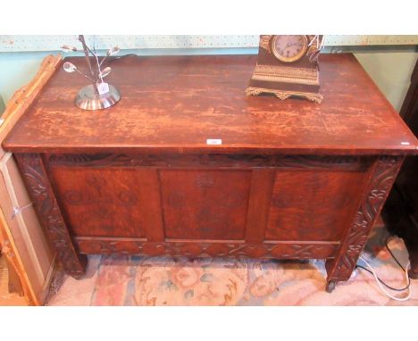 An 18th century-style oak coffer, the planked rising top over florally carved frieze and stiles, three panel front on later c
