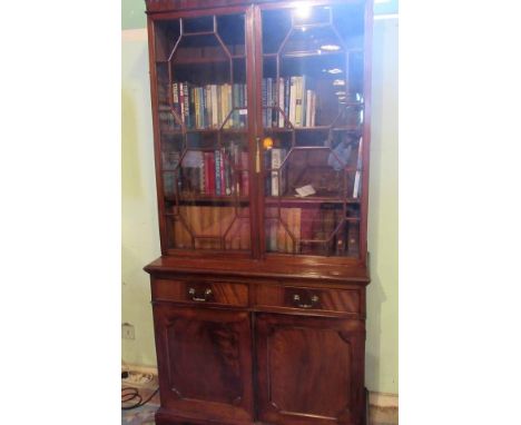 A George III-style mahogany bookcase cabinet, having dentil cornice over a pair of astragal glazed doors, enclosing three adj