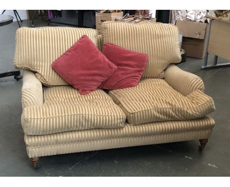 A good 20th century country house two seater sofa, on turned legs and brass casters, upholstered in a striped golden fabric, 