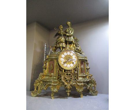 A mid 20th century French gilt brass mantle clock, the ornate case surmounted by a romancing couple, the dial with white and 