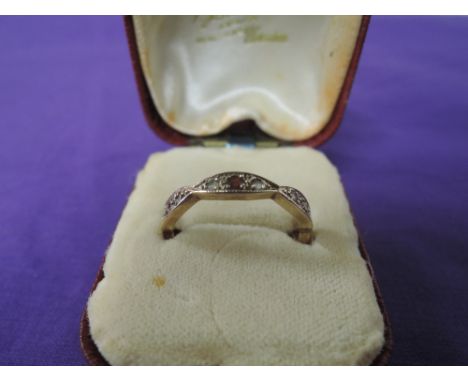 A yellow metal eternity ring of shaped form set with garnets and CZ,  size Q