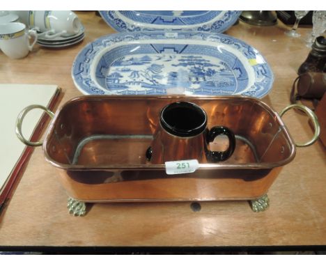 A copper planter with brass handles and lion feet