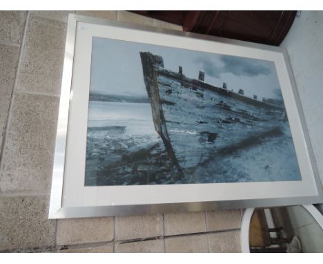 A large photographic print beached boat in metal effect frame