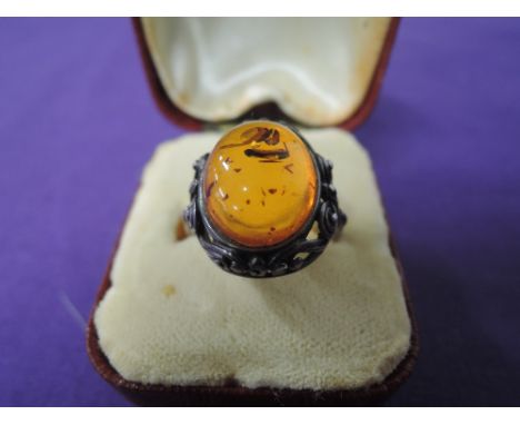 A lady's dress ring having an oval Baltic amber stone in a decorative moulded mount on a white metal loop stamped 925, size Q