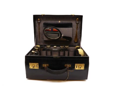 A black leather travelling vanity set,by Mappin &amp; Webb, London 1921, comprising 7 gilt silver mounted bottles, 4 brushes,