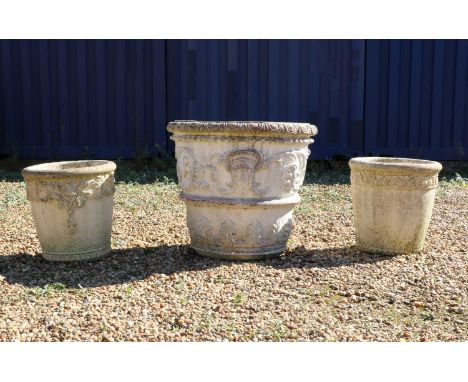 A group of three composite stone garden urns,comprising; a large relief moulded example,80cm diameter71cm hightogether with a