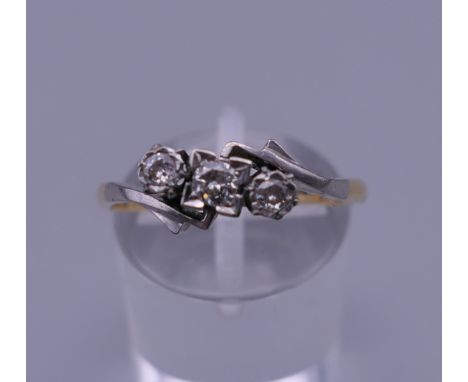 An 18 ct gold and platinum three stone diamond ring. Ring size R/S. 2.6 grammes total weight.