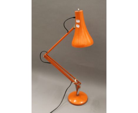 An orange angle poise lamp. 