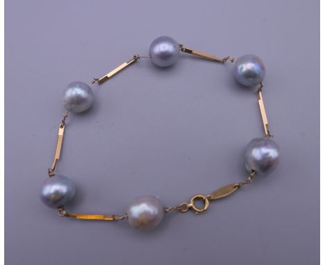 An 18 K gold and black pearl bracelet. Approximately 18 cm long.