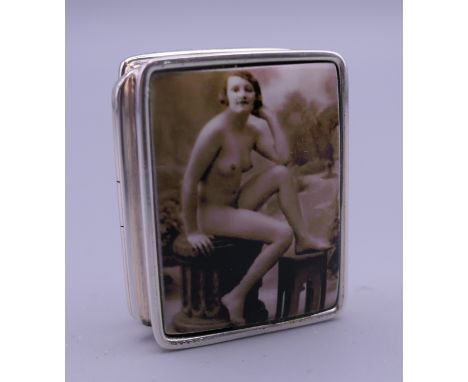 A silver pill box depicting a nude. 3 cm wide.