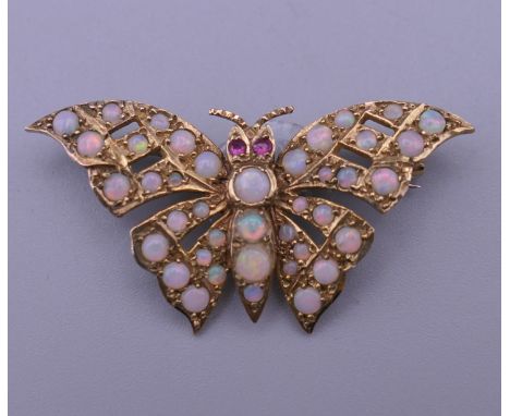 A 9 ct gold opal and ruby set butterfly brooch. 4 cm wide. 6 grammes total weight.