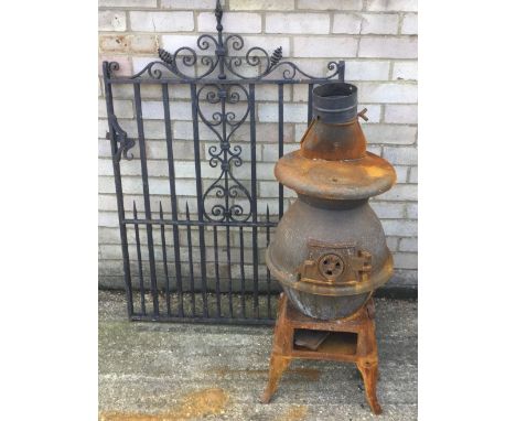 A vintage pot belly log burner and a wrought iron gate