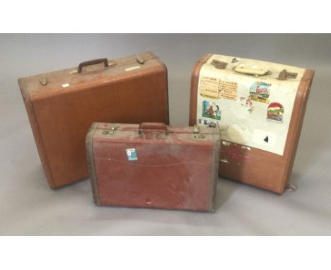A quantity of vintage suitcases, some with liner stickers