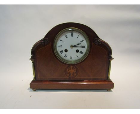 An Edwardian mantel clock, with black Roman numerals to the white enamelled dial, the movement striking on a gong; the arched