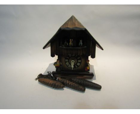 A late 20th Century wood-effect novelty cuckoo clock, with gallery of revolving dancers beneath the roof. 27cm tall. With thr