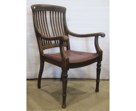 An Edwardian oak elbow chair with stick back and upholstered seat on turned supports