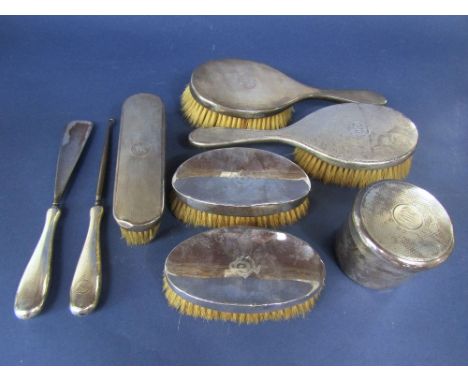 Matched eight piece silver engine turned dressing set comprising five brushes, lidded pot and silver lace hook and shoe horn