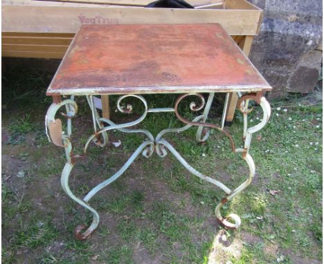 A contemporary weathered light steel garden table with square top raised on a scrolled and painted framework 