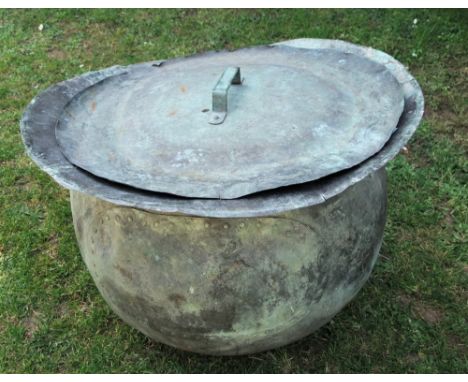 An old weathered copper cauldron of circular form with flared rim and riveted patch, complete with removable lid, approx 68 c