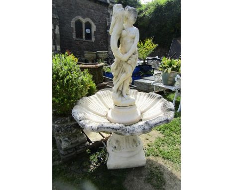 A large composition stone sectional garden fountain in the form of a standing classical maiden holding a stylised dolphin, ra