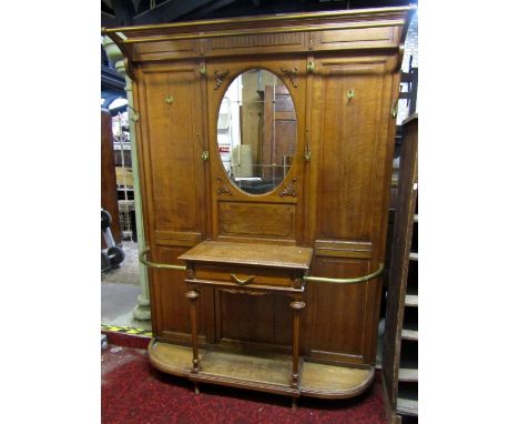 A substantial oak hall stand, central mirror panel, frieze drawer and D end stick stands with panelled back and further brass