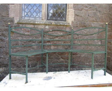 A contemporary Georgian style green painted light steel three seat garden bench of crescent form with rail back and strap wor