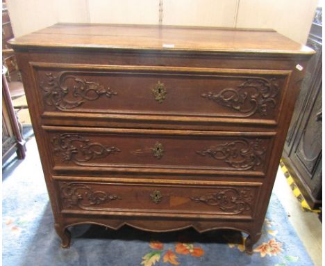 A 19th century oak continental commode of three long drawers, with carved detail on short cabriole supports, 108cm wide