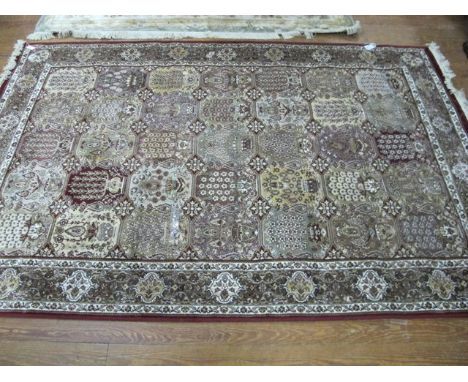 A WOOL RUG the light grey and wine ground with floral panels within a conforming border 235cm x 135cm